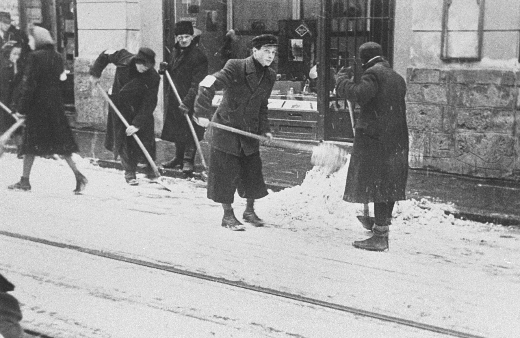 Jews wearing armbands are forced to shovel snow from the pavement in