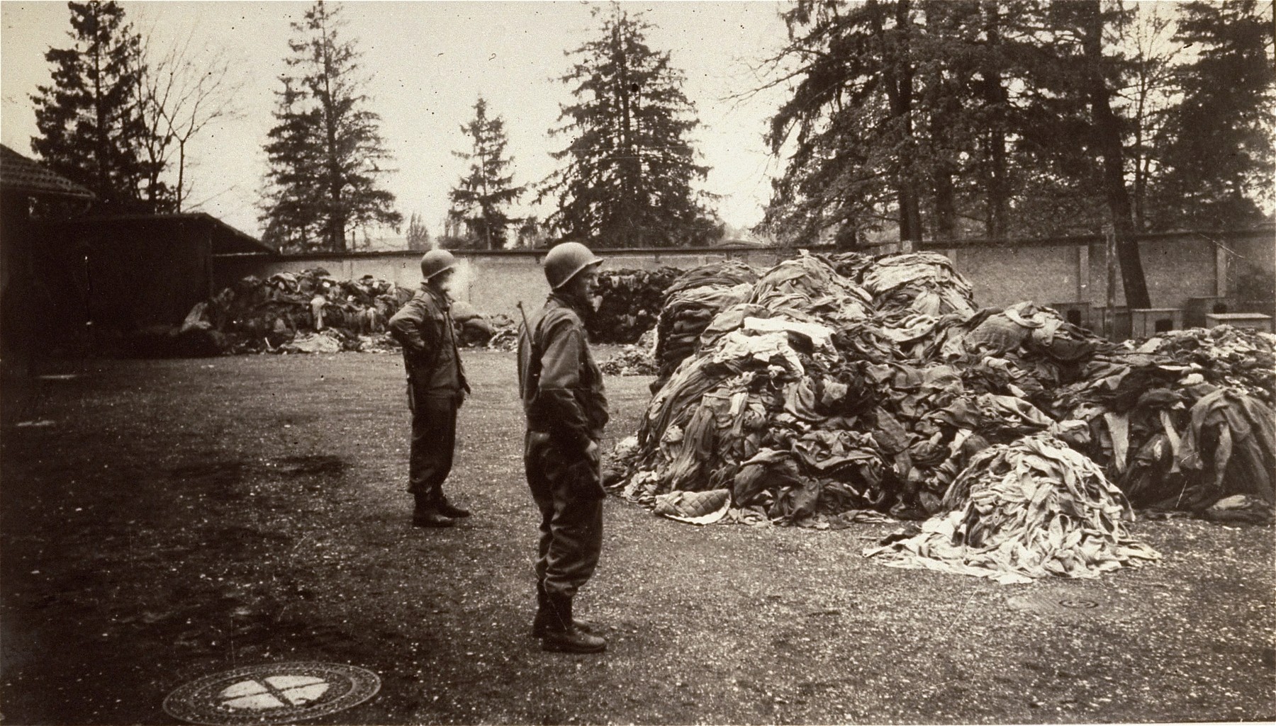 American soldiers in Dachau examine piles of prisoners' clothing found