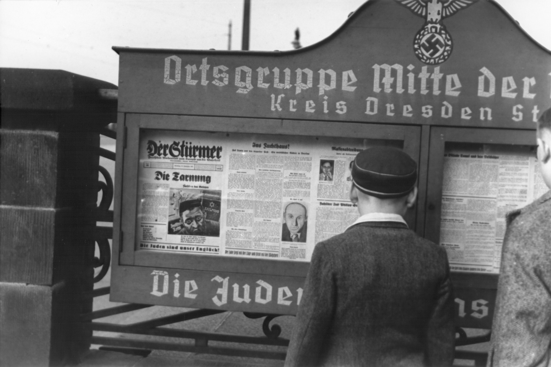 German boys read an issue of the Stuermer newspaper that is posted in a