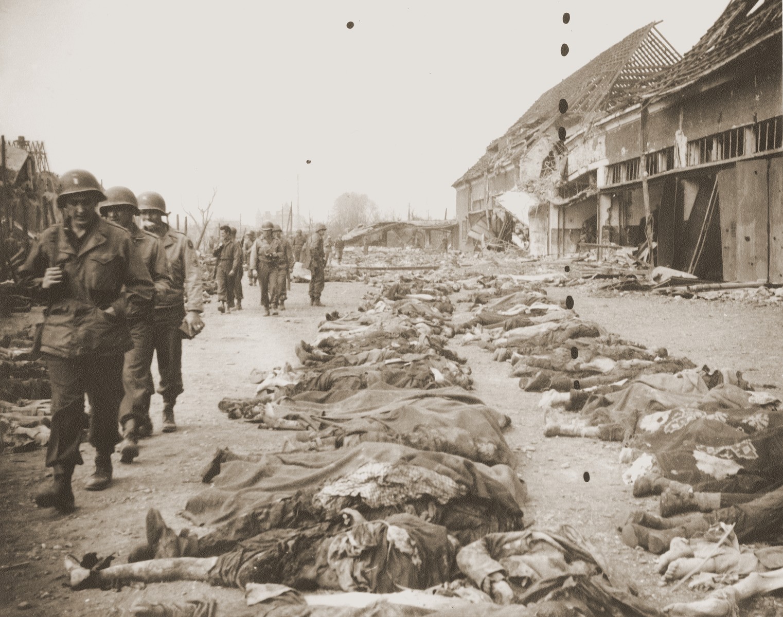 American soldiers file past the bodies of prisoners killed in the