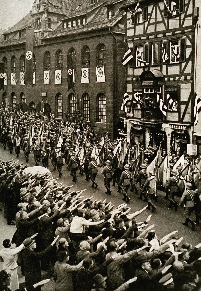 German troops parade through the streets carrying military banners