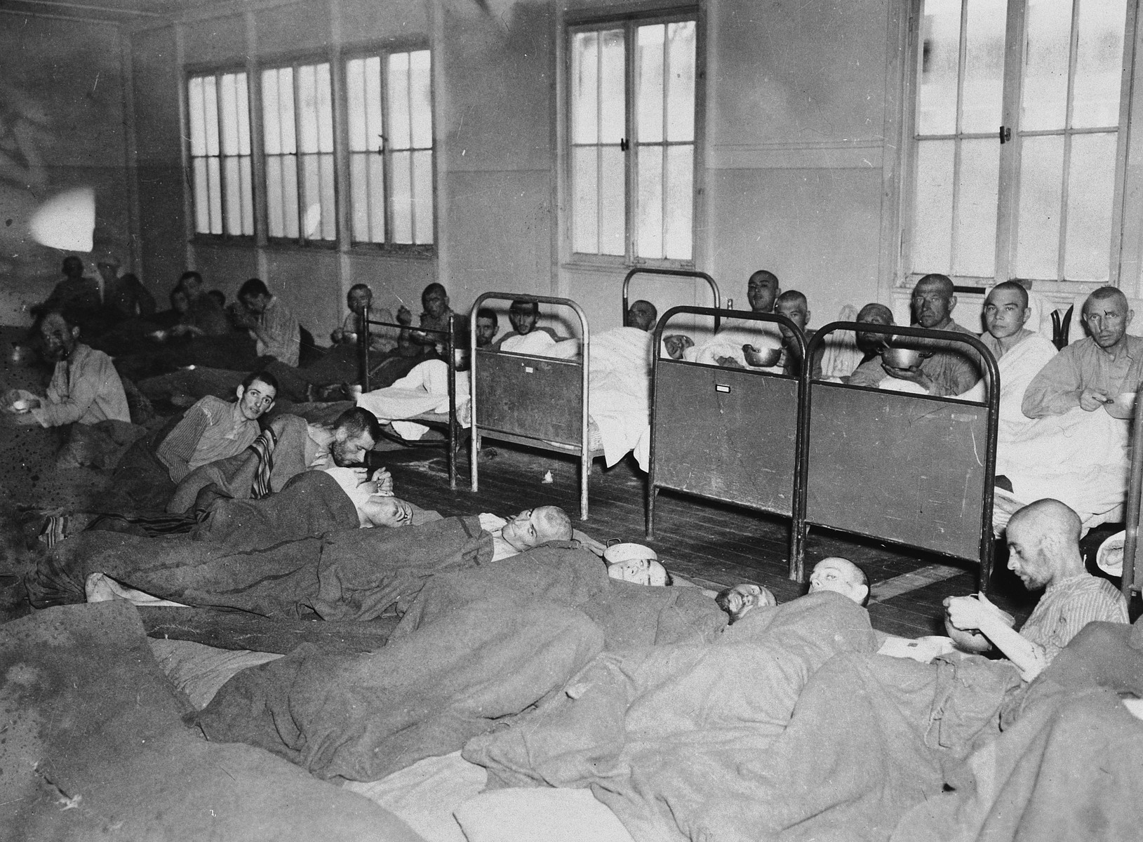 Infirmed survivors lie on cots and on the floor in the infirmary of the