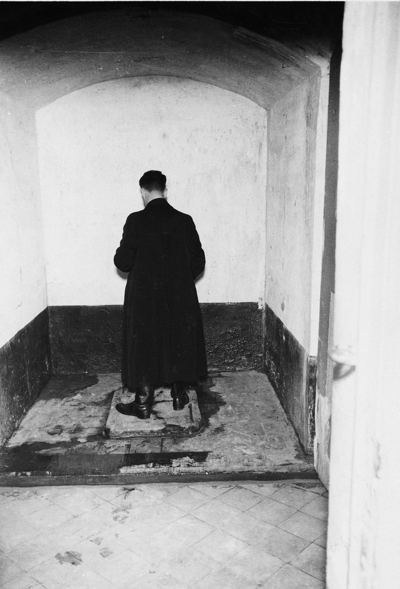 A survivor reenacts the treatment of prisoners in a torture chamber in the Breendonck