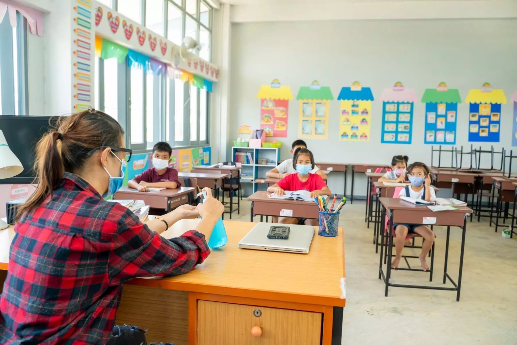 A teacher shows students proper hand sanitizing to help prevent the spread of COVID-19 in her classroom