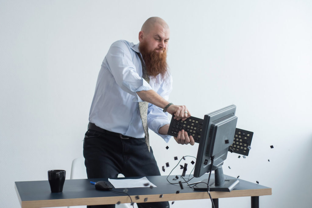 Angry bald man with a red beard in the office in a business suit