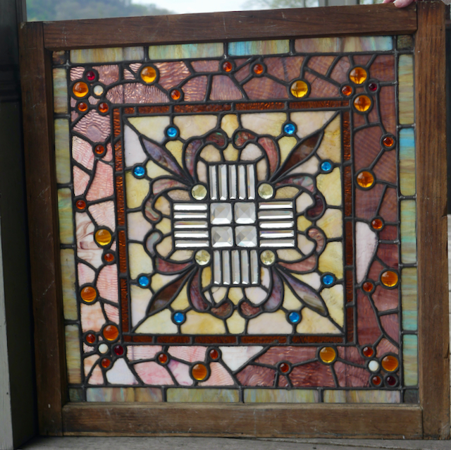 Heavily jeweled antique stained glass window with combination of both