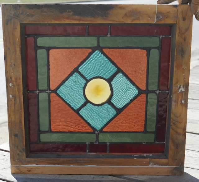 Small antique stained glass window with roundel center.