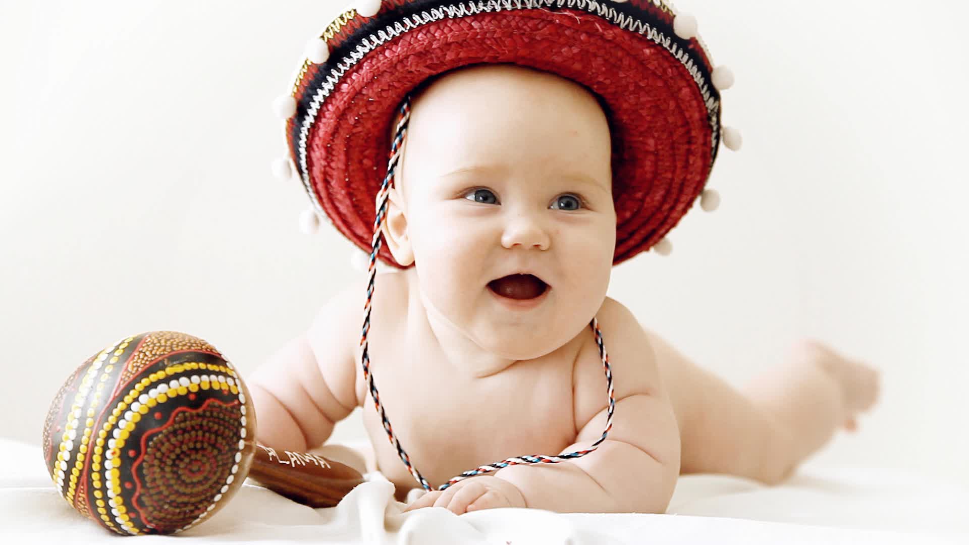 Baby in sombrero hat with maracas on the light background Hi Res