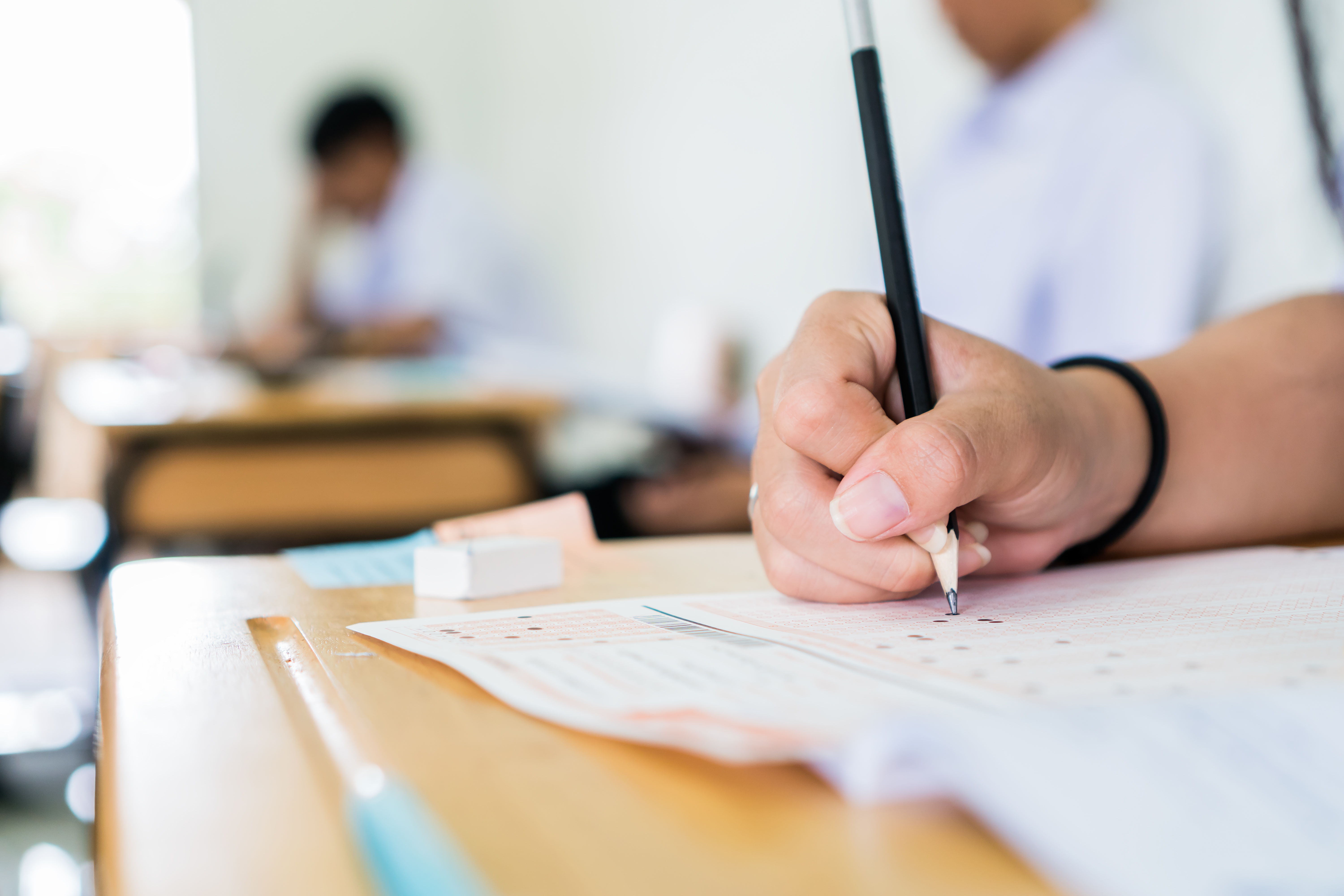 High school university student holding pencil writing exam on paper