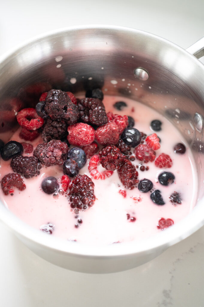 Frozen mixed berries in a saucepan with a cornstarch slurry.