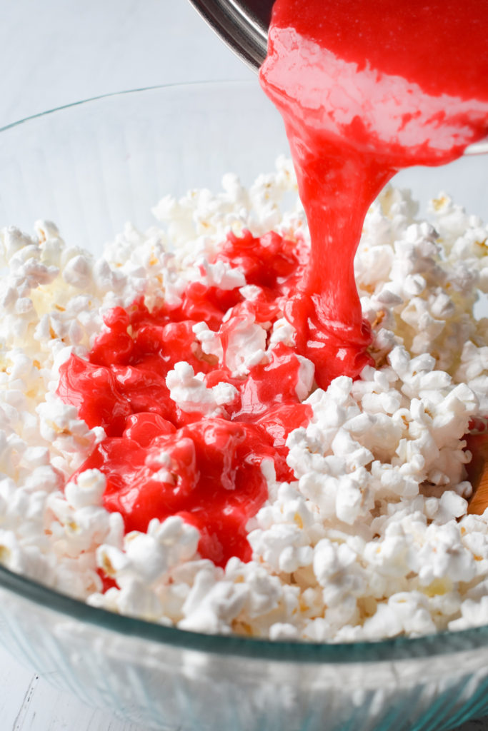 melted ingredients being poured over popped popcorn