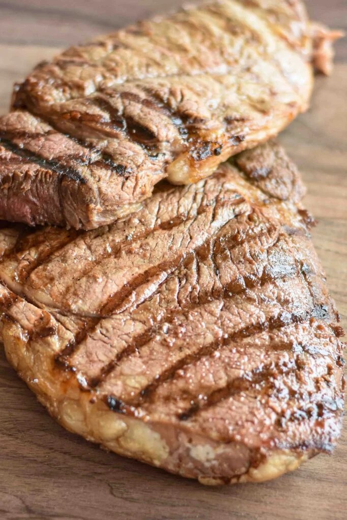 Steak resting on a cutting board after being grilled.