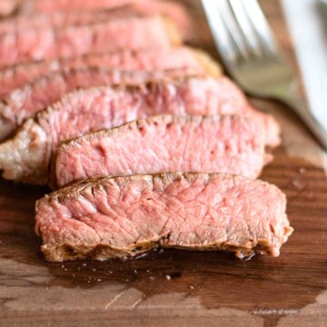 Slices of juicy steak on a cutting board.