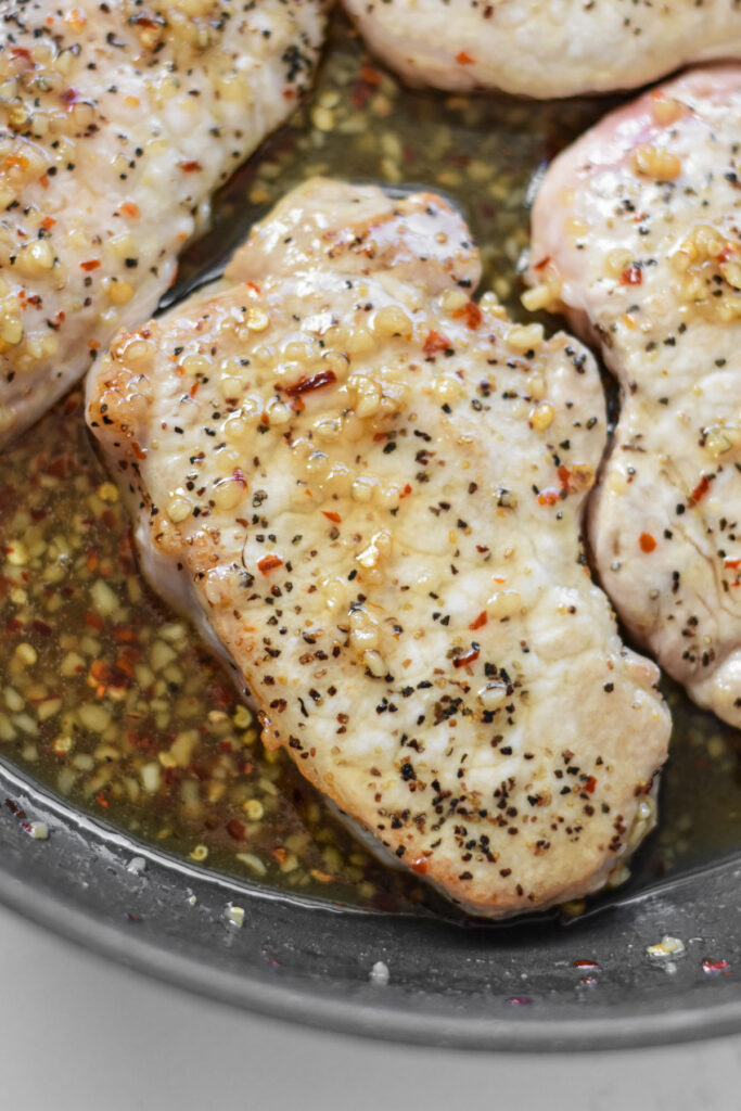 Boneless chops cooking in a honey garlic sauce.