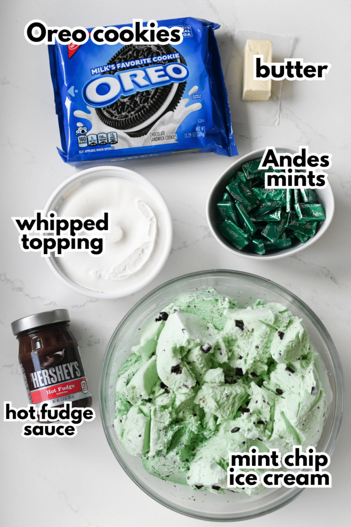 The ingredients needed to make a mint oreo ice cream dessert on a white countertop with labels.