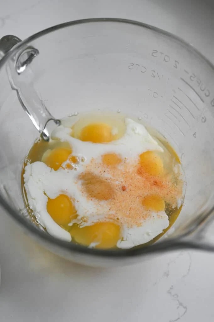 Eggs, milk, and seasoned salt in a clear glass bowl.