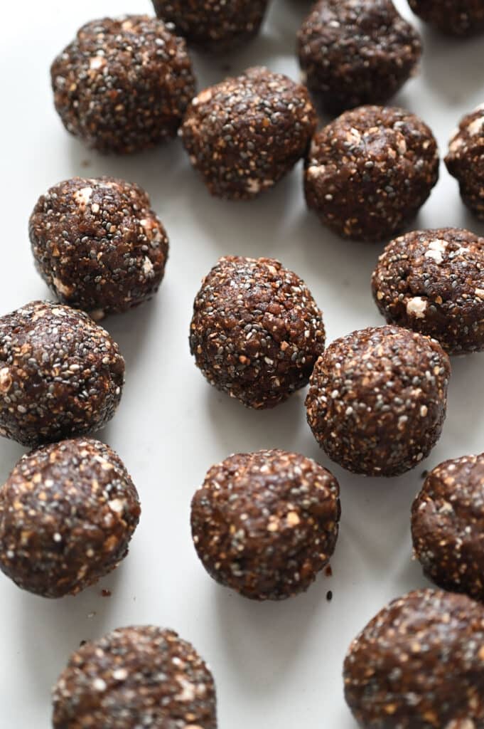 Chocolatey energy bites rolled into balls on a white countertop.