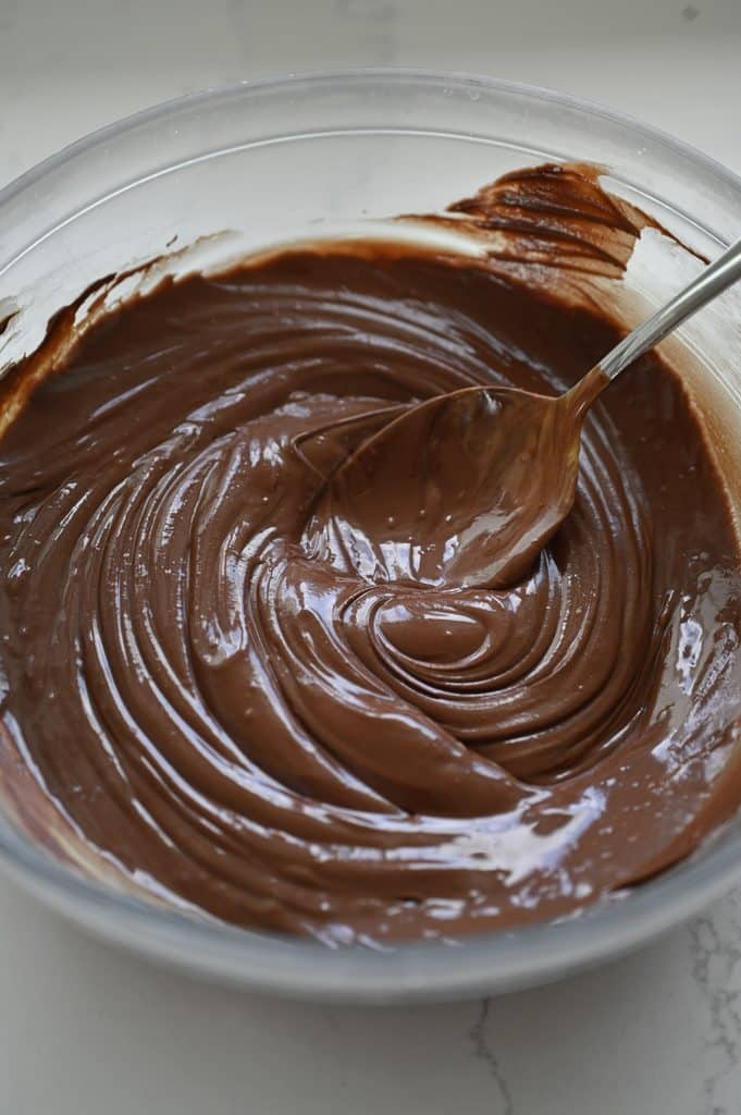 Melted chocolate in a clear glass mixing bowl.