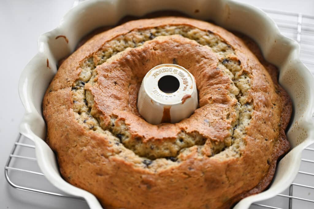 A cooked bundt cake in a pan on a wire rack.