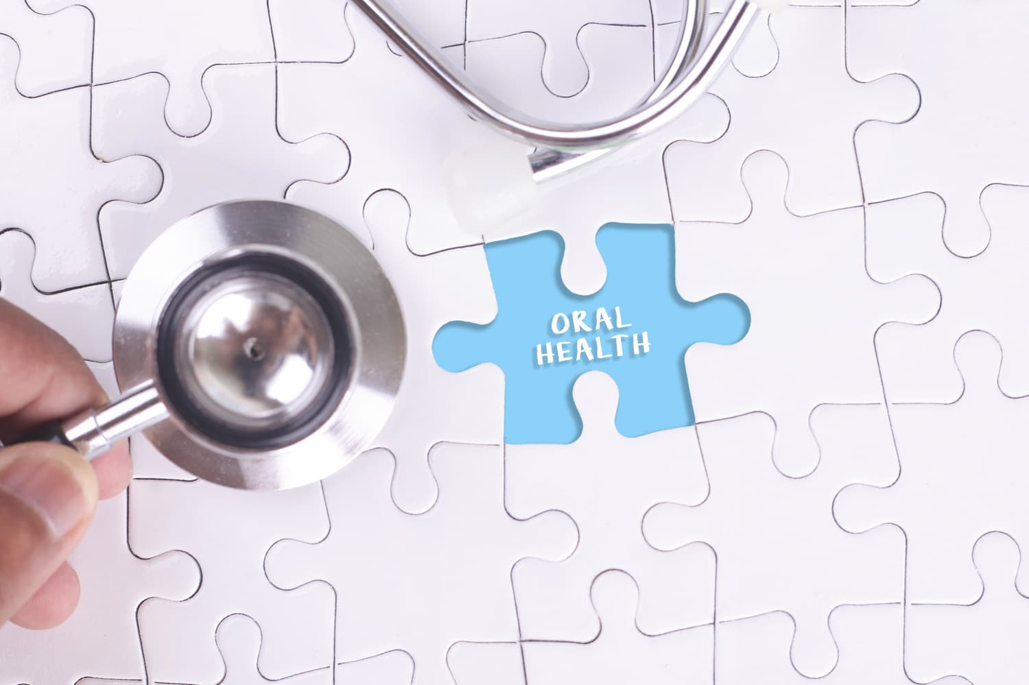 Doctor holding a Stethoscope on missing puzzle WITH ORAL HEALTH Dr