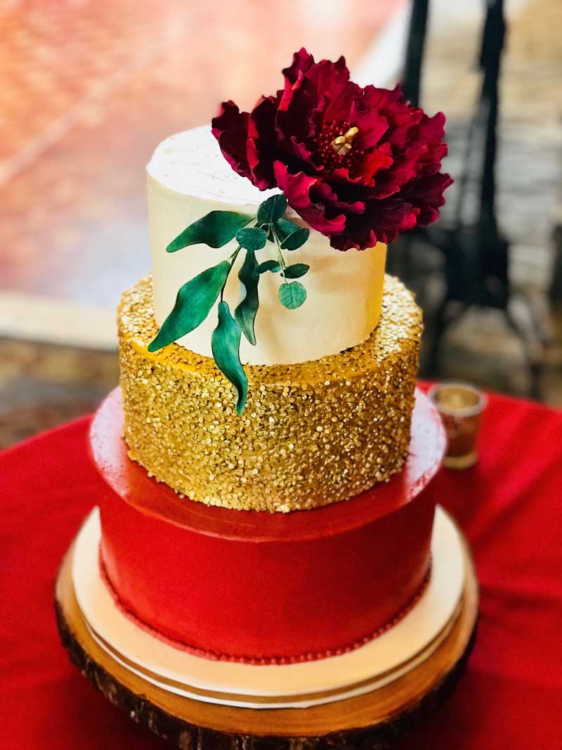 Gold sequins and buttercream wedding cake with a beautiful giant peony and green leaves