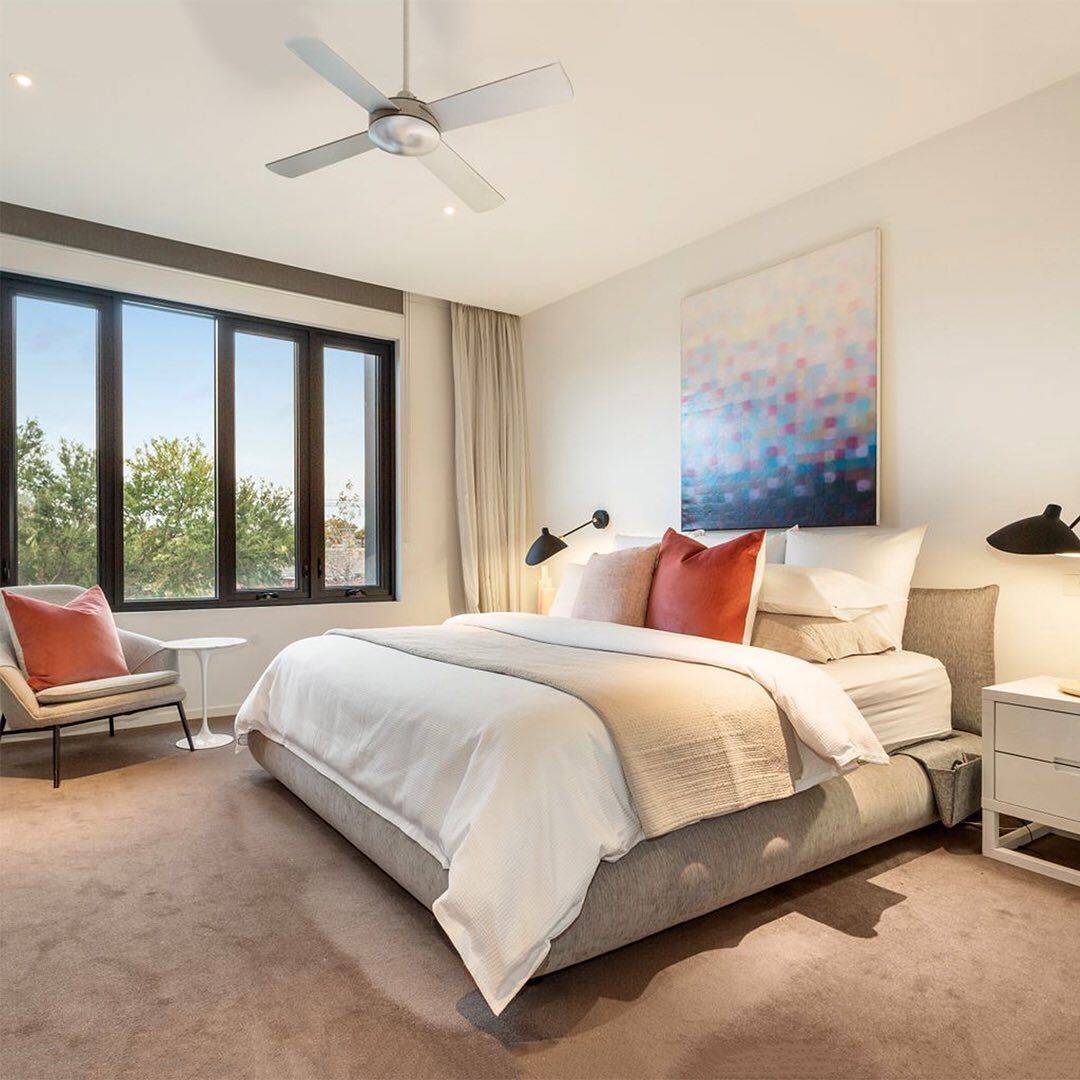 A lofty master bedroom contains a neutral color palette of