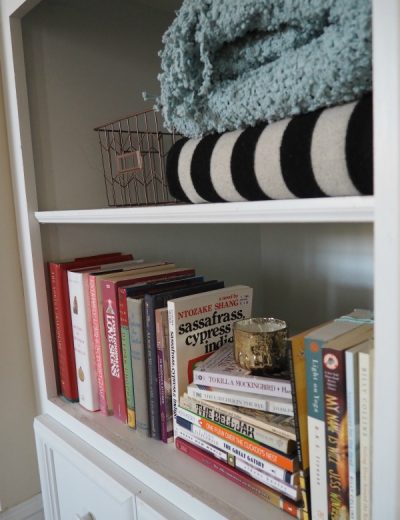a bookshelf with books and blankets
