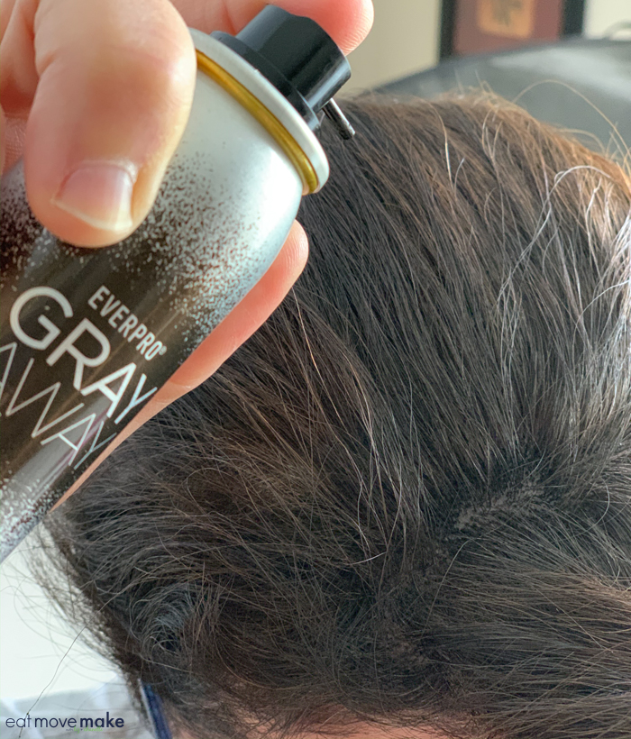 A close up of a person spraying hair with gray hair