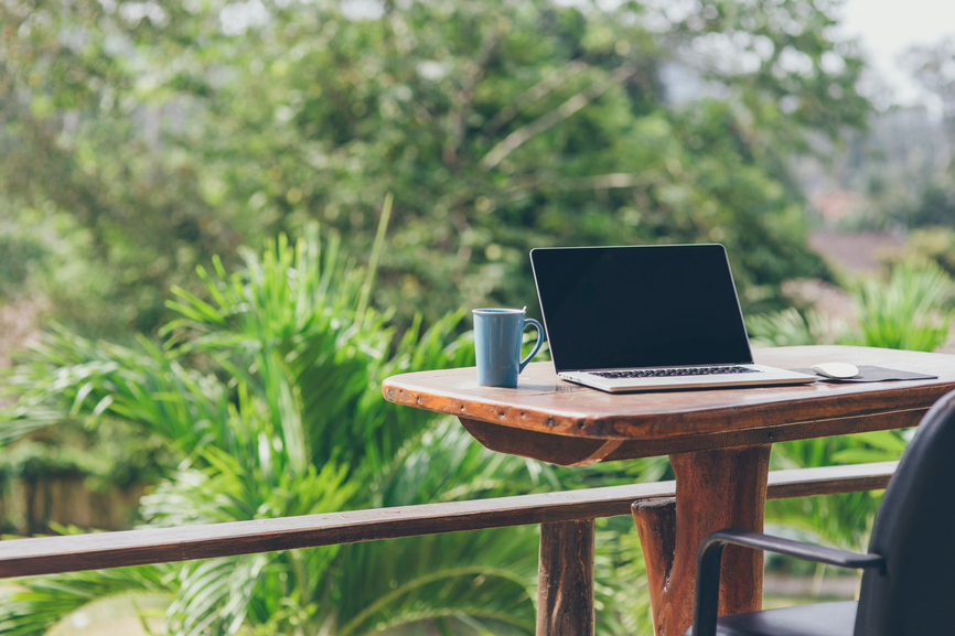 Outdoor office with laptop computer on wooden table and blue cof