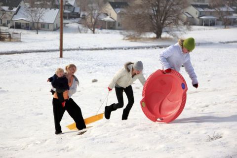 Teens and children sledding in the snow