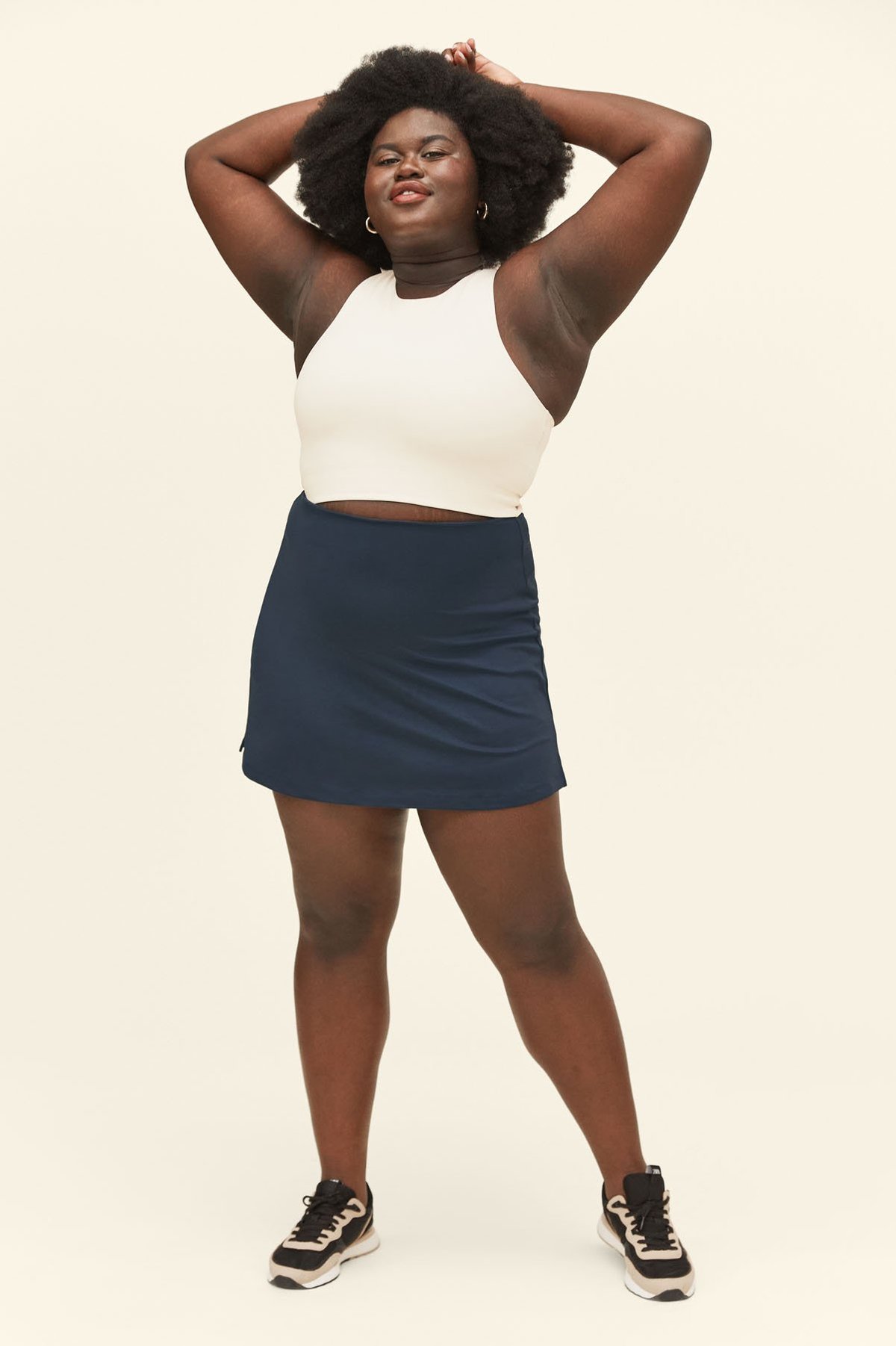 Brands that don't retouch their models. This model from Girlfriend Collective wears a navy skort and shows off the stretch marks on her dark skin.