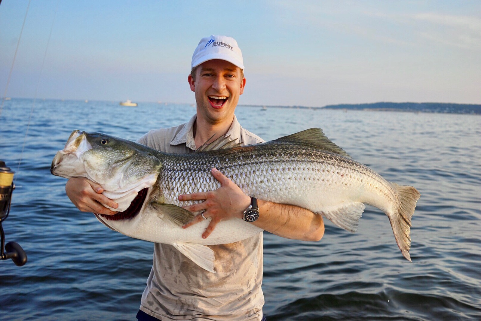 an smiling angler holding a striped bass on a boat