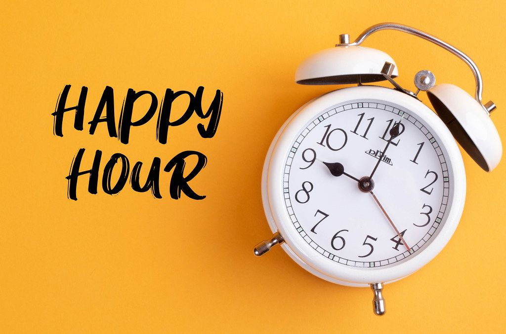 Alarm clock with handwritten Happy Hour text on yellow background