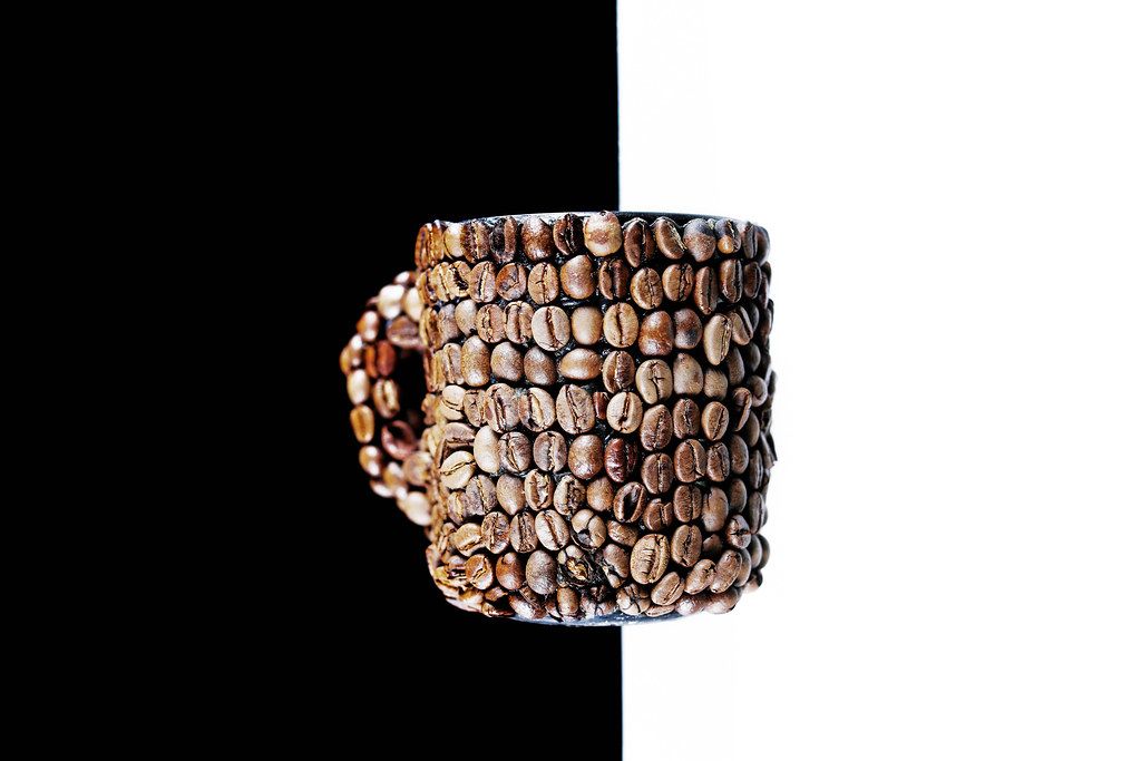 Coffee beans cup, background split in black and white Creative