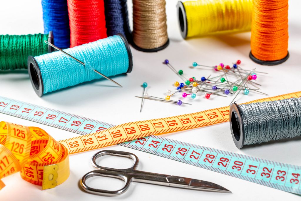 Colored sewing thread and bobbin with measuring tape, scissors and