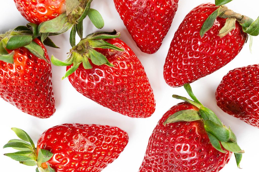 Fresh Strawberries served on the plate with strawberry in the hand