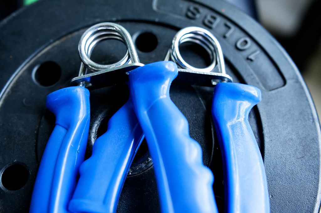 Exercise hand grips hanging on gym weight bar Creative Commons Bilder