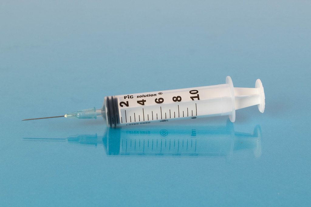 Medical syringe on blue background Creative Commons Bilder