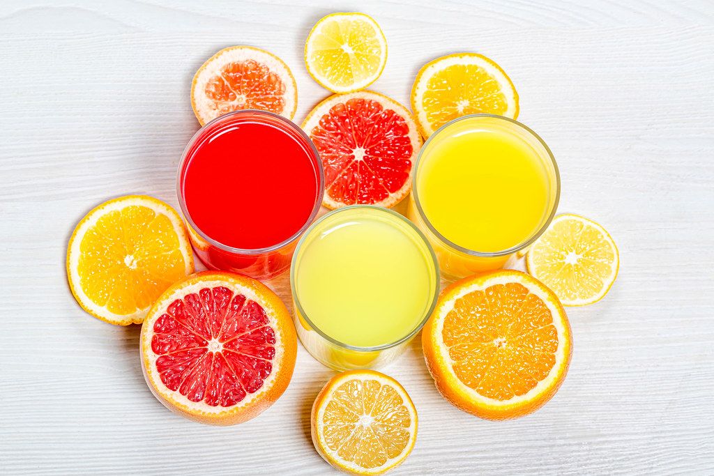 Top view orange, lemon and grapefruit juices with slices of fresh