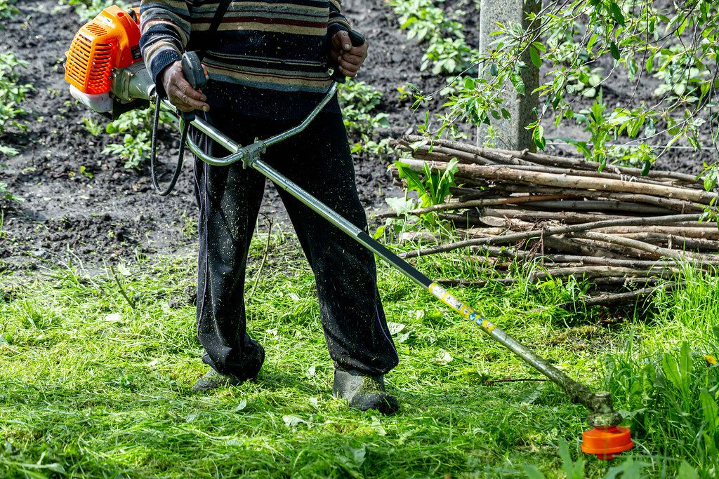 A man mows grass with an old electric lawn mower Creative Commons Bilder
