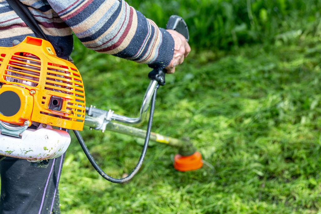 A man mows grass with an old electric lawn mower Creative Commons Bilder