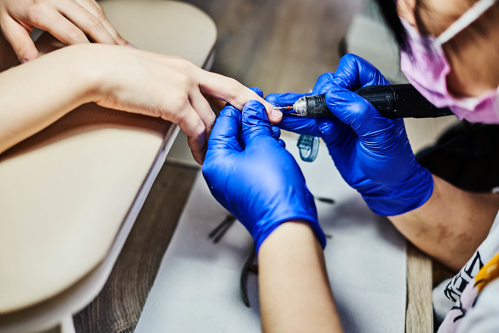 Closeup professional beautician hands working with electric drill file