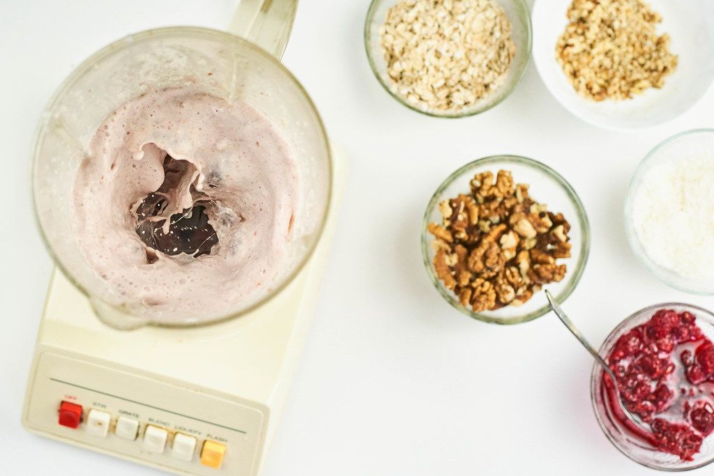 Preparing oats, walnuts, and raspberry based milkshake with blender