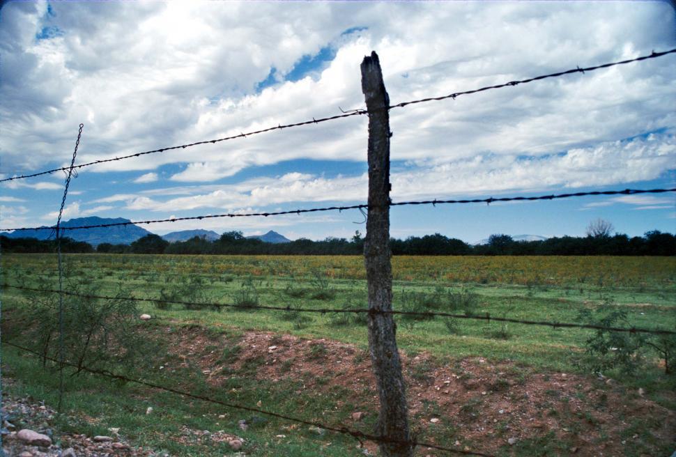 Free Stock Photo of barbed wire fence posts clouds fields plains
