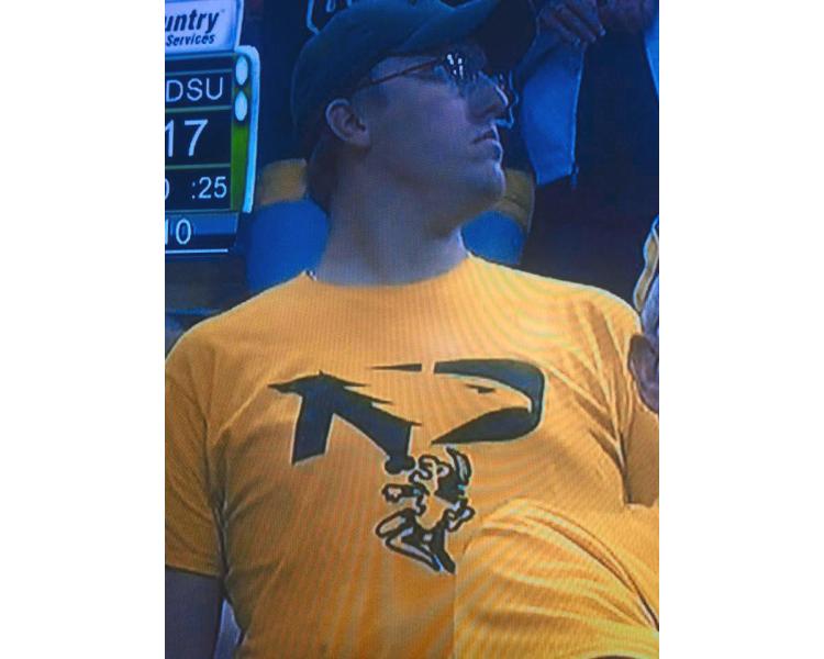 WDAY.com News - Screen Capture. A North Dakota State University supporter was spotted at a football game Nov. 5 with an obscene T-shirt, modified with the University of North Dakota’s new Fighting Hawks logo altered with a single-feathered Native figure on its knees before a phallus extending from the Bison logo.