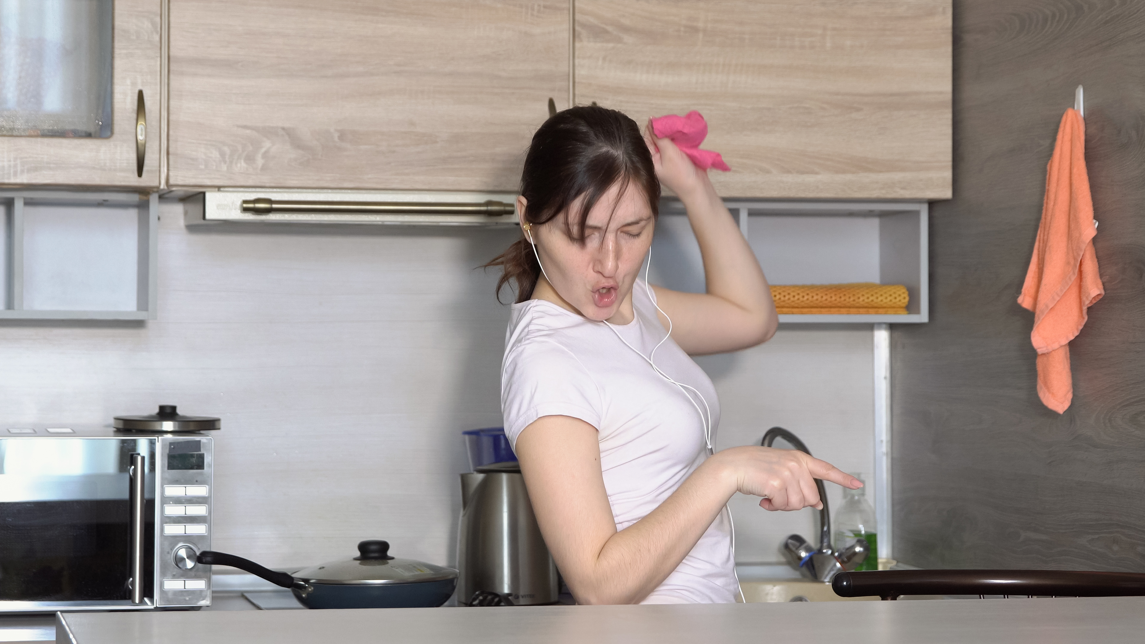 Beautiful woman is cleaning in the kitchen, dancing to the Beautiful woman is cleaning in the kitchen, dancing to the