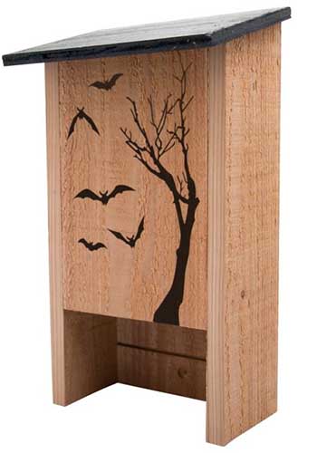 A close up vertical image of a wooden bat house with a silhouette pictured on the front, pictured on a white background.