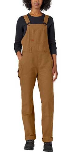 A close up vertical image of a woman wearing brown overalls over a black shirt.