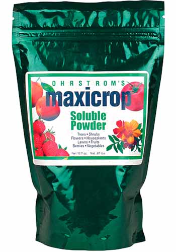 A close up vertical image of the packaging of Maxicrop Soluble Powder isolated on a white background.