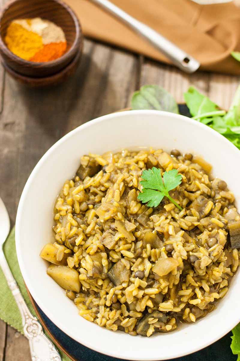 A close up vertical image of a freshly prepared dish of rice and lentils on a wooden surface.